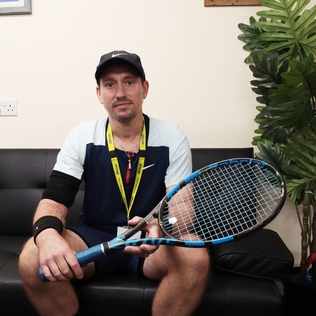 Portrait of Marc, an EDP volunteer with the Flourish in Nature project with his tennis racket
