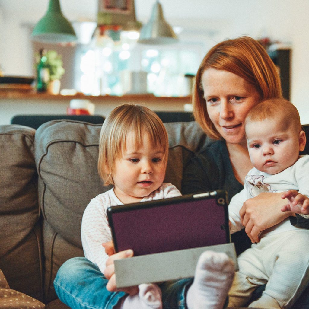 A mother showing her two children something on a computer tablet