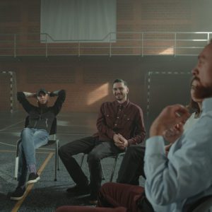 A group of people talking informally, sat in chairs in a circle