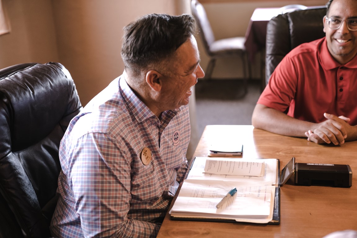 recovery worker sitting with someone with an open book on the desk and both are laughing